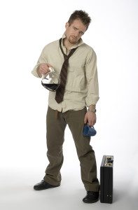 Man standing with wrinkled shirt, loose necktie, coffee pot, and briefcase