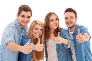 Group of happy young people showing thumbs up, isolated on white background